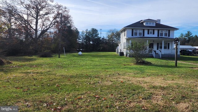 exterior space with cooling unit, covered porch, and a front yard