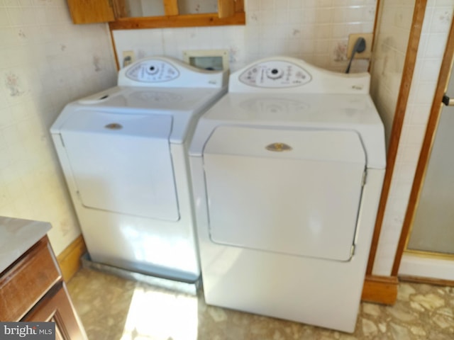 laundry room featuring separate washer and dryer and tile walls