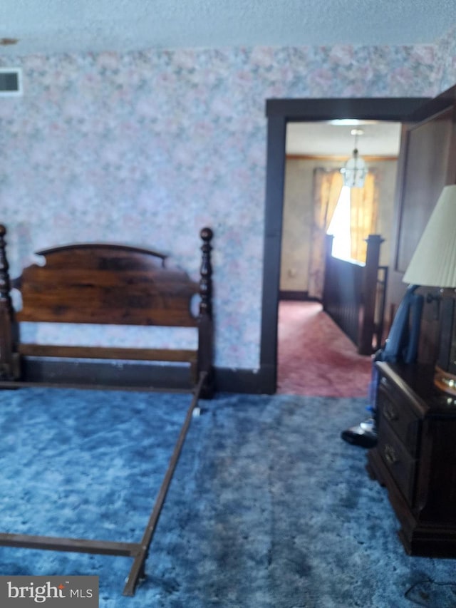 carpeted bedroom with a chandelier and a textured ceiling