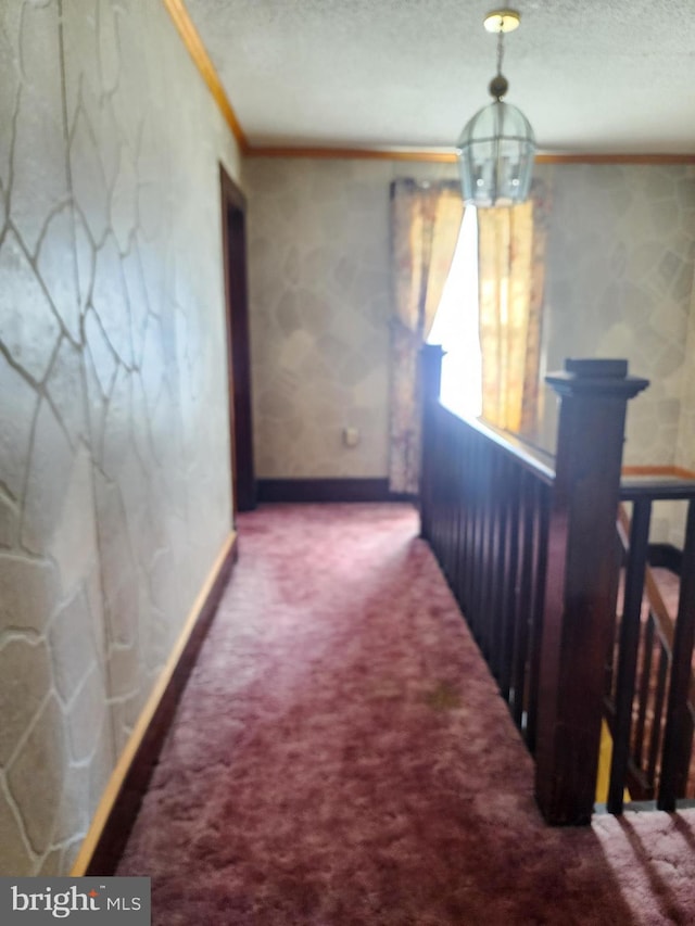 hall featuring a chandelier, a textured ceiling, carpet floors, and ornamental molding