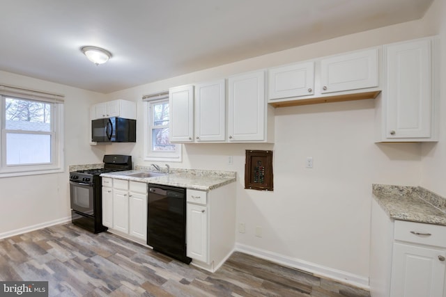 kitchen with sink, white cabinetry, light hardwood / wood-style flooring, and black appliances