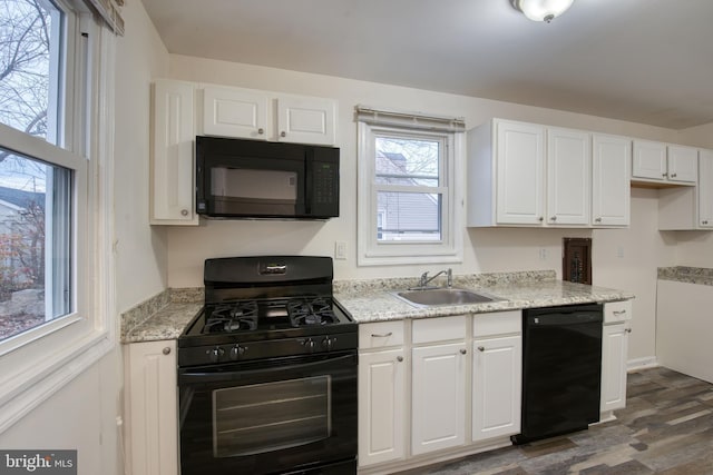 kitchen with light stone counters, sink, black appliances, white cabinets, and dark hardwood / wood-style floors