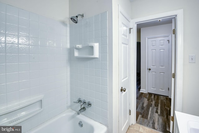 bathroom with tiled shower / bath combo, wood-type flooring, and vanity