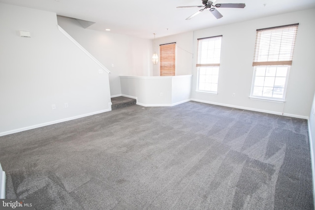 unfurnished room with ceiling fan and dark colored carpet