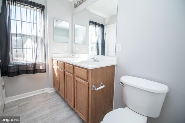 bathroom featuring toilet, a wealth of natural light, and vanity