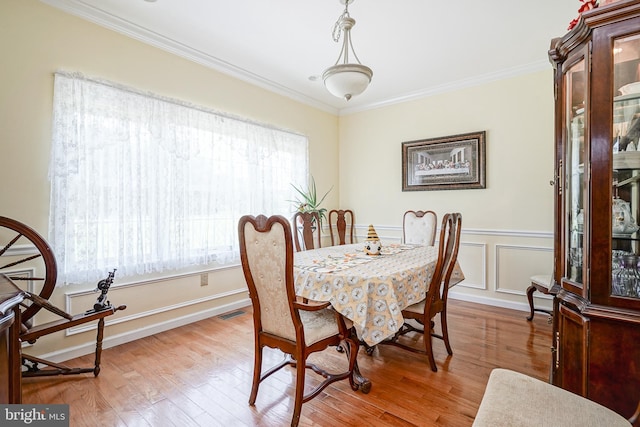 dining area with a healthy amount of sunlight, ornamental molding, and light hardwood / wood-style flooring