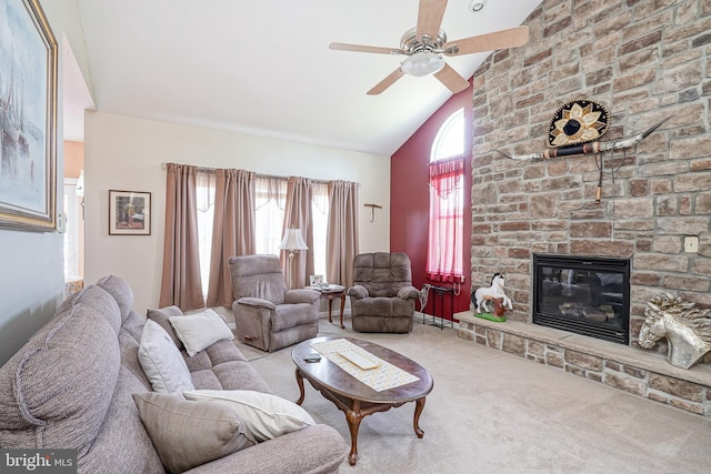 living room featuring light colored carpet, vaulted ceiling, ceiling fan, and a stone fireplace