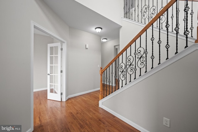 stairs with french doors and hardwood / wood-style flooring