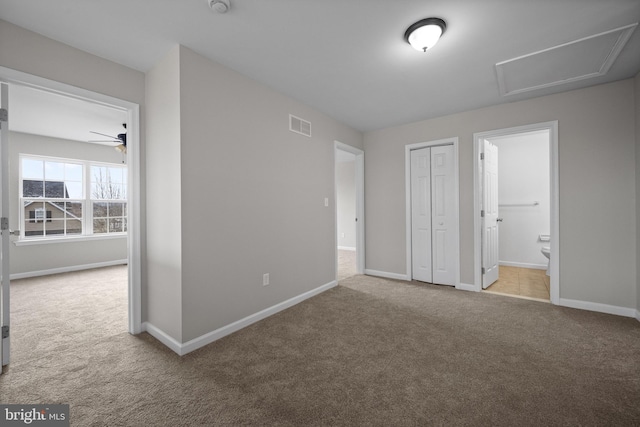 unfurnished bedroom featuring a closet, light carpet, and ensuite bath