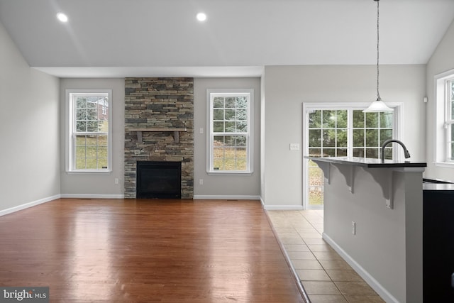 unfurnished living room with a fireplace, wood-type flooring, lofted ceiling, and sink