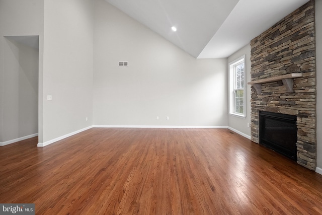 unfurnished living room featuring dark hardwood / wood-style flooring, a stone fireplace, and vaulted ceiling