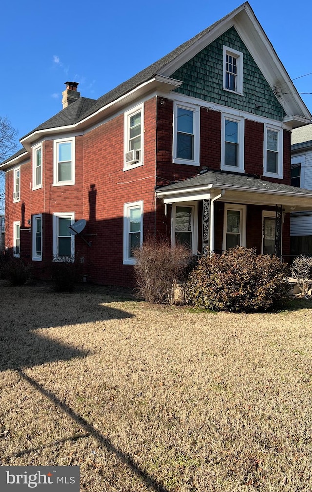 exterior space featuring brick siding, a chimney, and a front yard