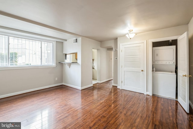 interior space with stacked washer / drying machine and dark hardwood / wood-style floors