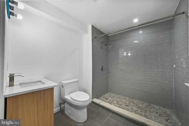 bathroom featuring tile patterned flooring, toilet, a tile shower, and vanity