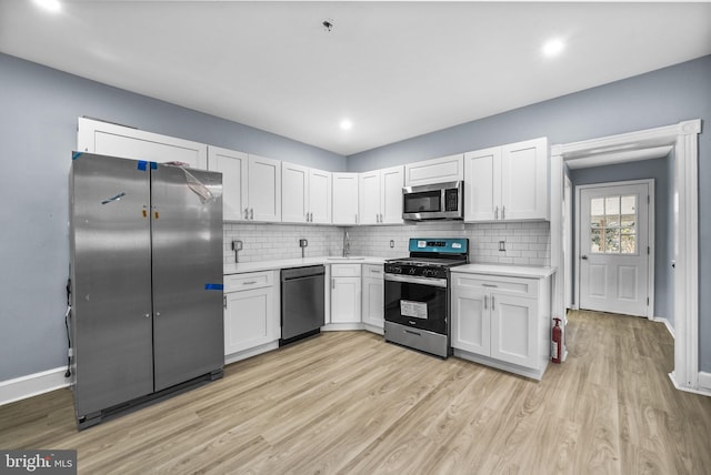 kitchen featuring tasteful backsplash, stainless steel appliances, sink, white cabinets, and light hardwood / wood-style floors