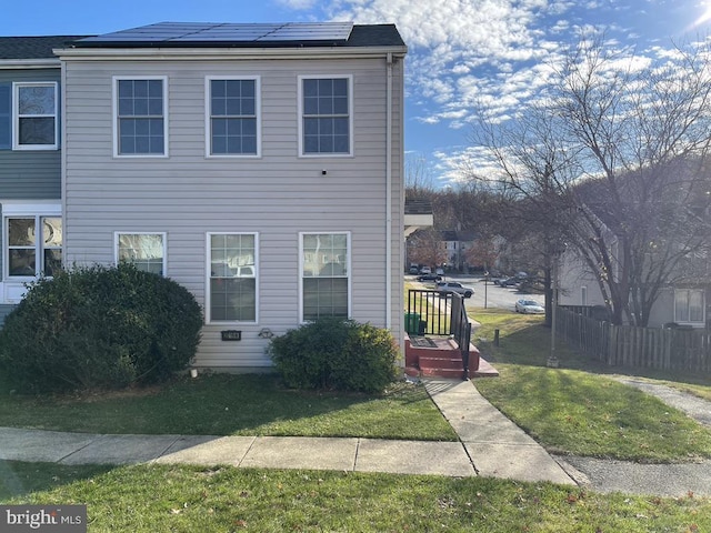 view of front of property featuring a front lawn and solar panels