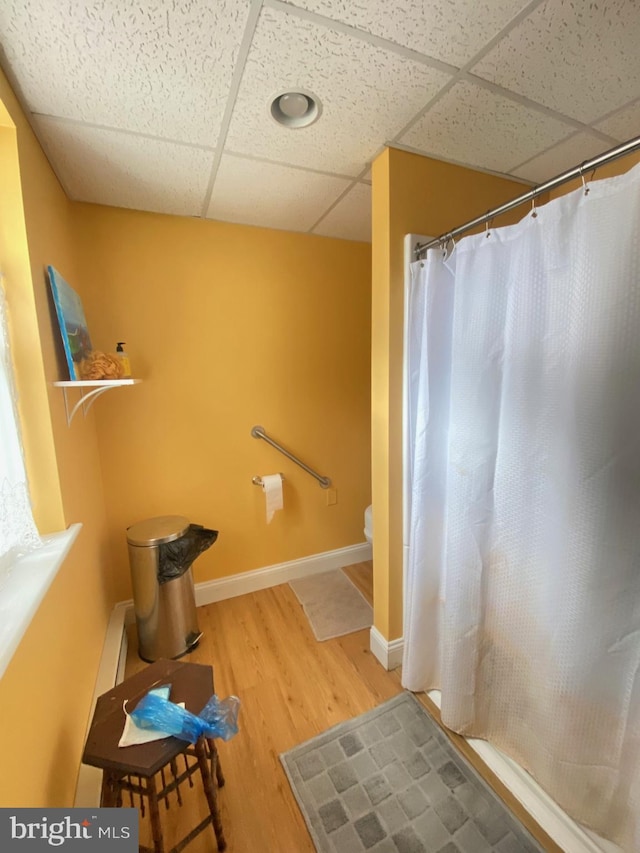 bathroom with hardwood / wood-style flooring, a drop ceiling, and toilet