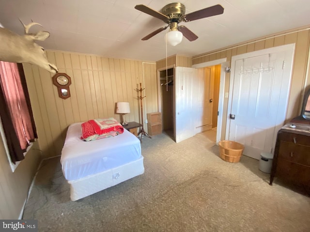 carpeted bedroom featuring a closet, ceiling fan, and wood walls