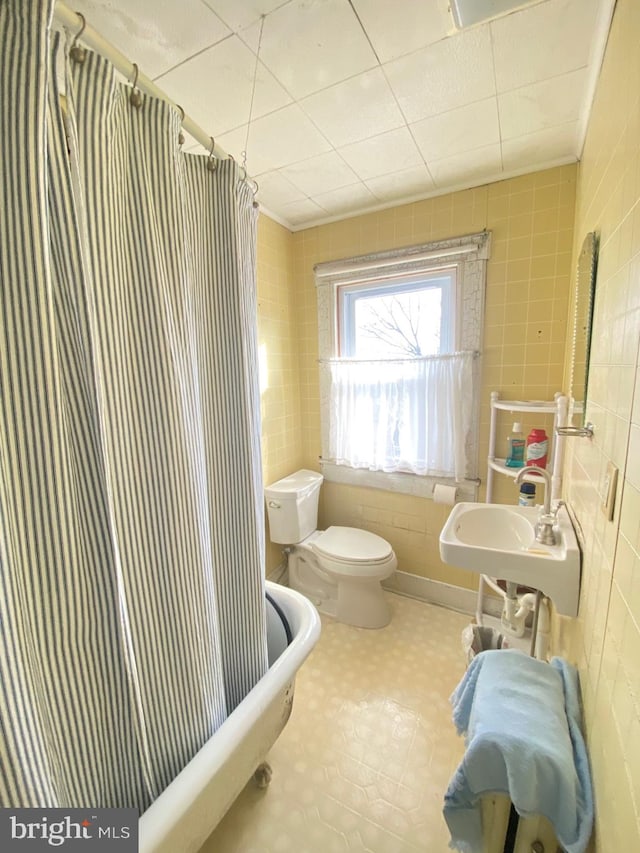 full bathroom featuring sink, shower / tub combo, tile walls, and toilet