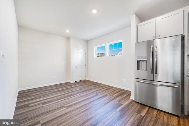 kitchen with hardwood / wood-style floors, stainless steel fridge, and white cabinetry