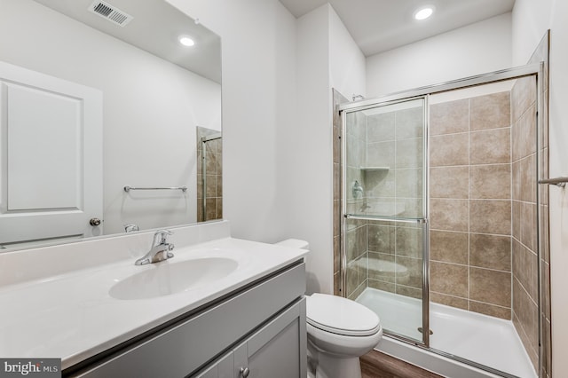 bathroom featuring a shower with door, vanity, wood-type flooring, and toilet