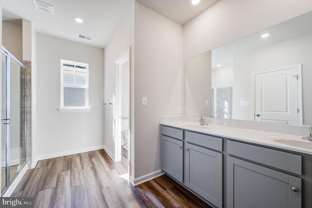 bathroom featuring hardwood / wood-style flooring, vanity, toilet, and an enclosed shower