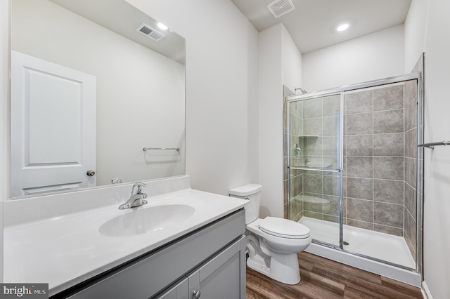 bathroom with hardwood / wood-style floors, vanity, a shower with door, and toilet