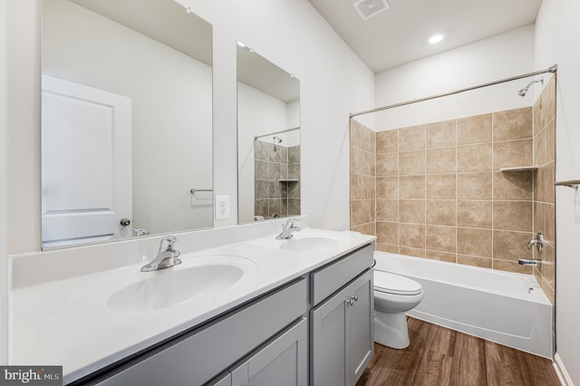 full bathroom with vanity, hardwood / wood-style floors, tiled shower / bath combo, and toilet