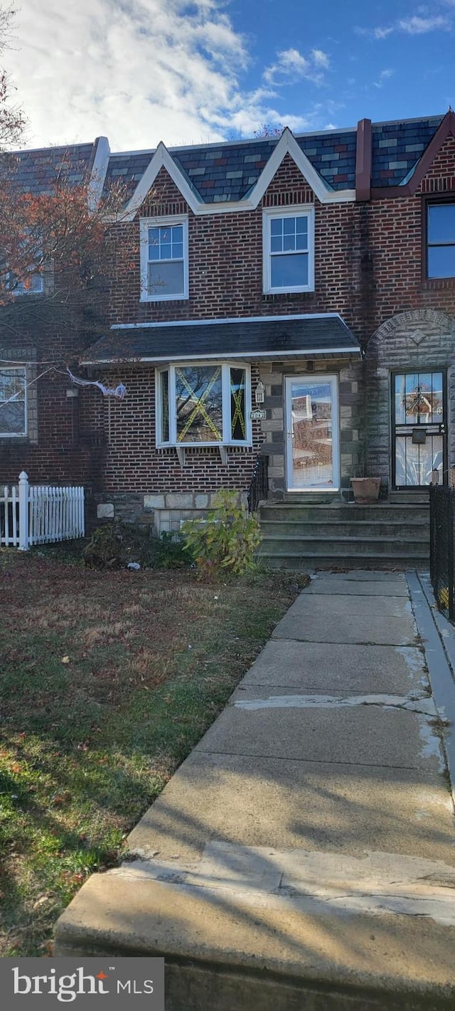 view of front facade featuring fence and brick siding