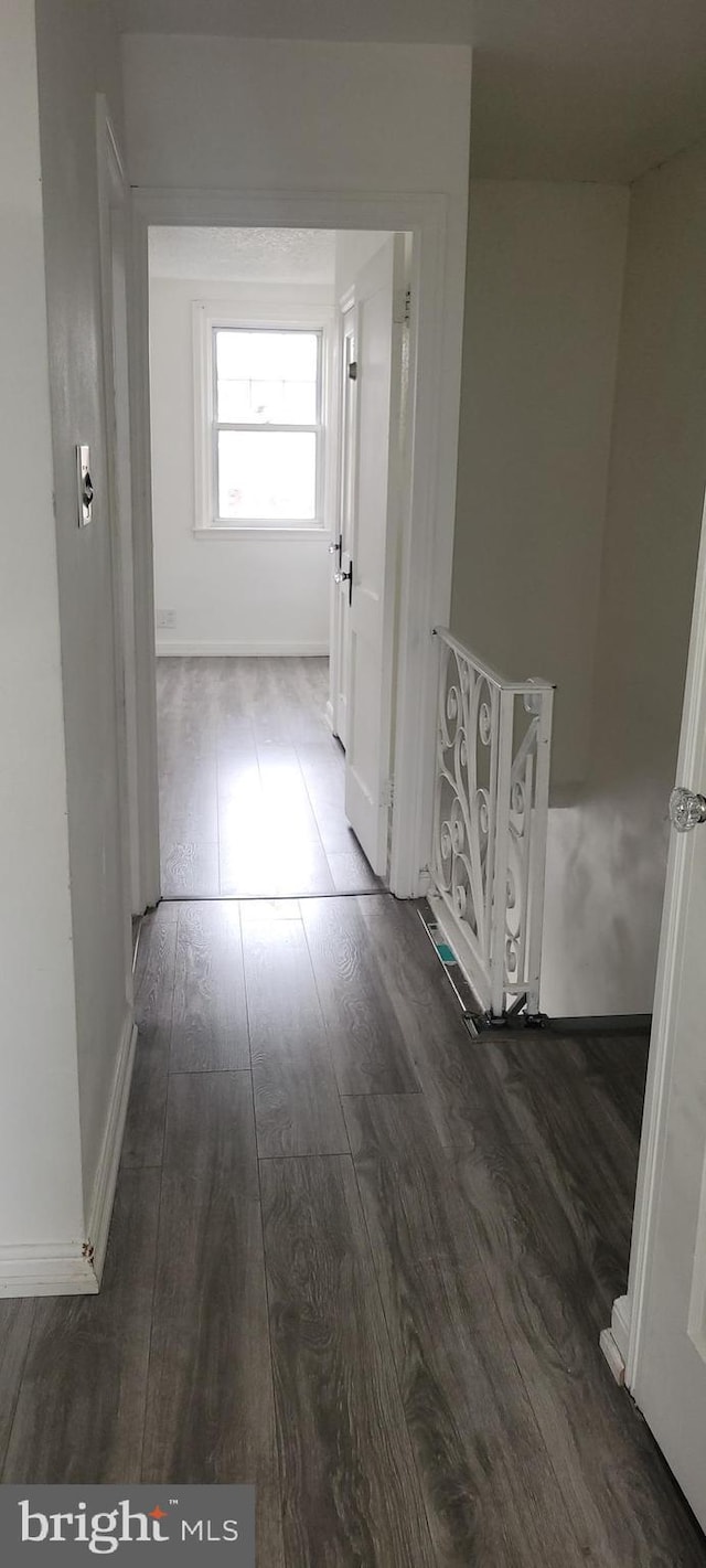 corridor featuring dark wood-type flooring and baseboards