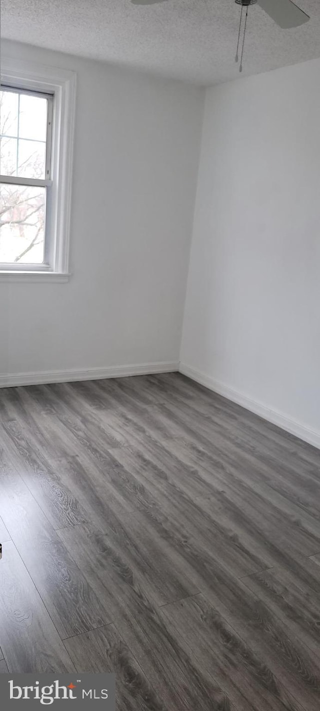 spare room featuring dark wood-style flooring, a textured ceiling, and baseboards