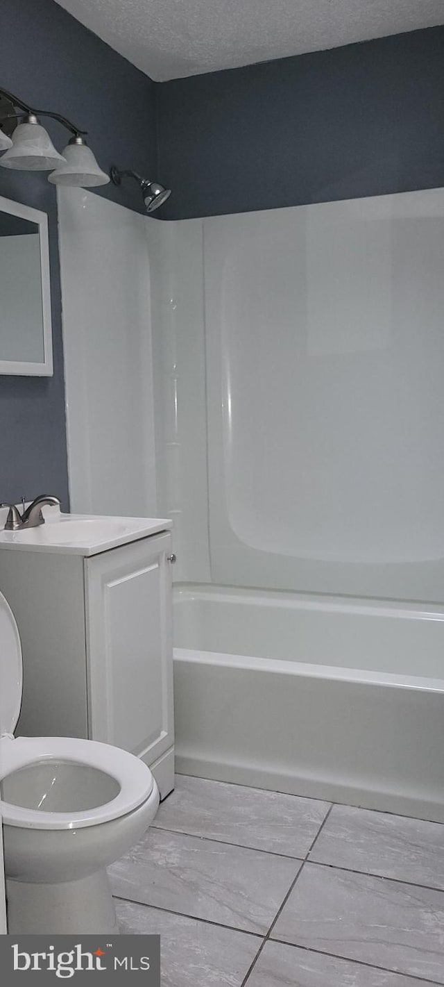 full bath with toilet, washtub / shower combination, a textured ceiling, and vanity