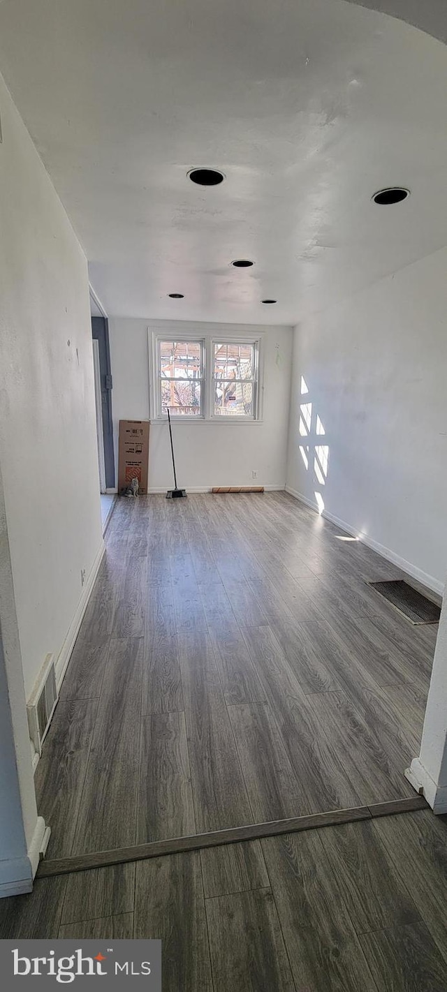 unfurnished living room featuring baseboards, visible vents, and wood finished floors