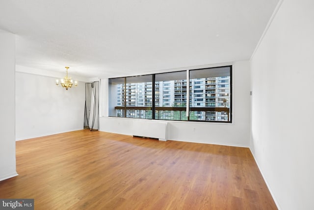 spare room with hardwood / wood-style floors and a notable chandelier