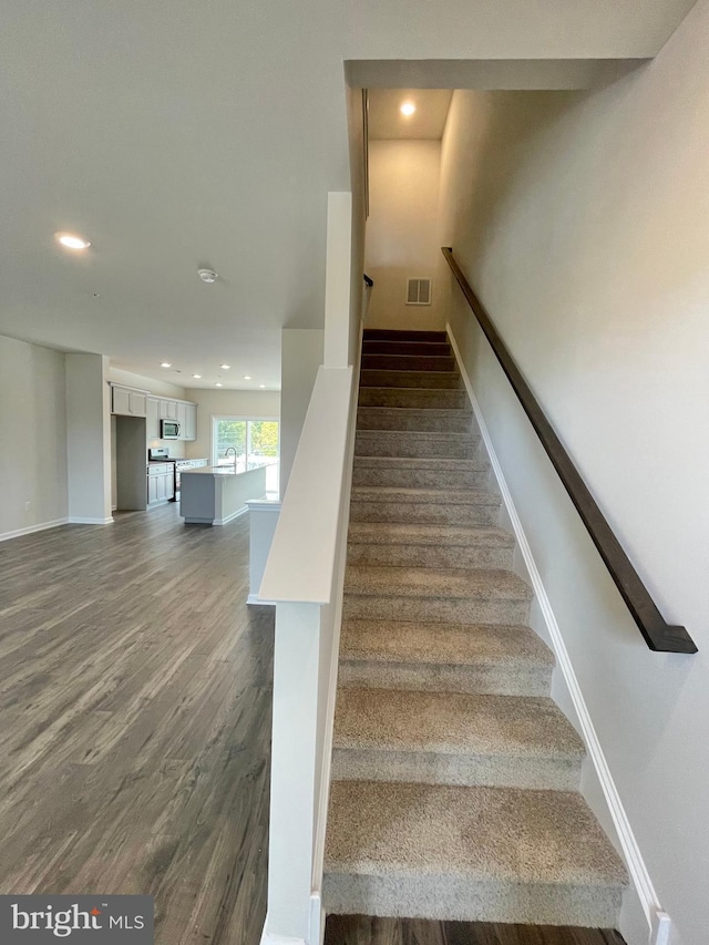 stairs with hardwood / wood-style floors and sink