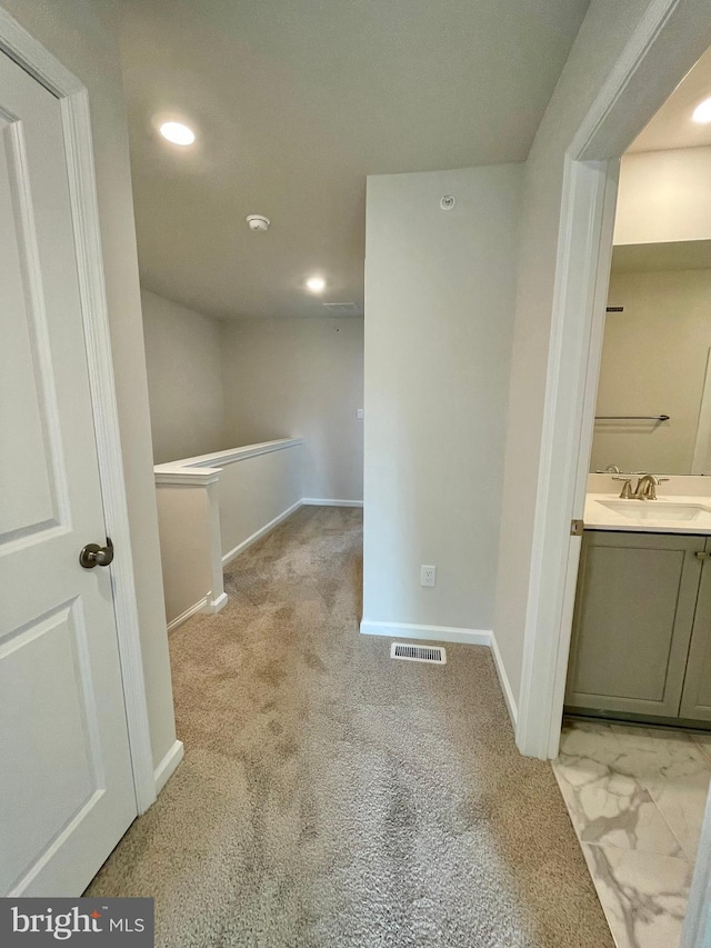 corridor featuring sink and light colored carpet