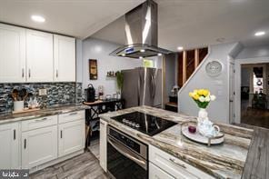 kitchen featuring white cabinets, light wood-type flooring, extractor fan, and stainless steel appliances