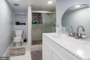 bathroom featuring toilet, walk in shower, and vanity