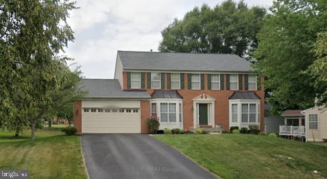 colonial-style house featuring a front yard and a garage