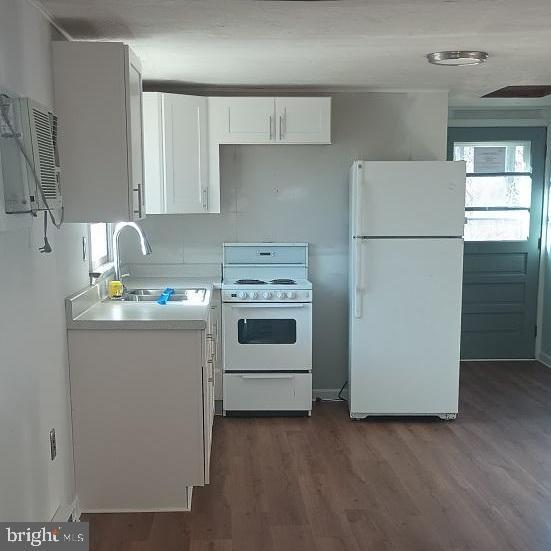 kitchen featuring white appliances, dark wood-type flooring, sink, an AC wall unit, and white cabinetry