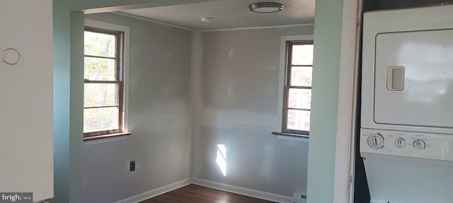 laundry area with dark hardwood / wood-style flooring, stacked washing maching and dryer, and ornamental molding