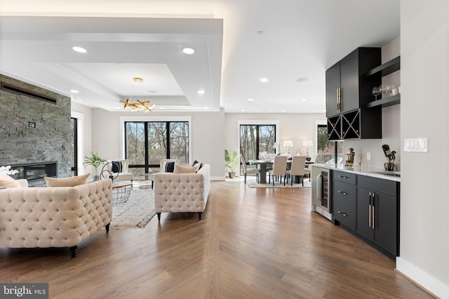 3113 Circle Hill Rd, Alexandria, VA 22305 - living area with beverage cooler, bar with sink, a stone fireplace, a tray ceiling, and a chandelier
