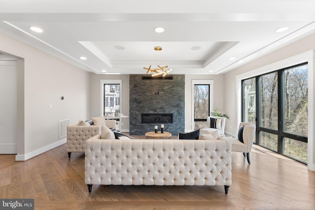 3113 Circle Hill Rd, Alexandria, VA 22305 - living room with a tray ceiling, a fireplace, light wood-style flooring, baseboards, and a chandelier