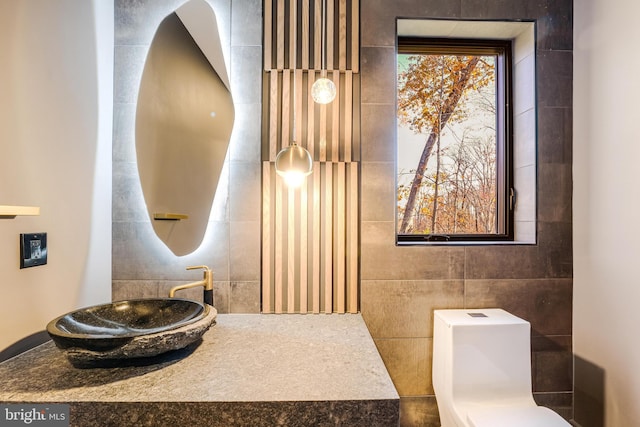 bathroom featuring sink, tile walls, and toilet