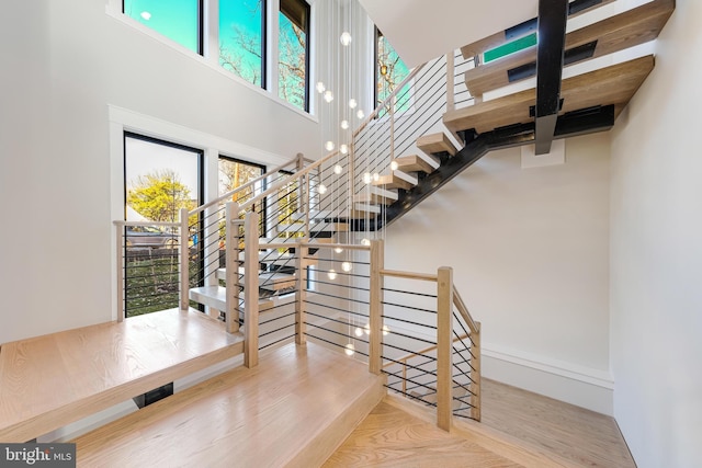 stairway featuring wood-type flooring and a high ceiling