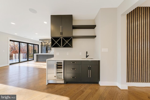 bar featuring light hardwood / wood-style flooring, beverage cooler, and sink