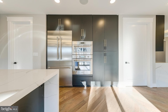 kitchen featuring light stone counters, light wood-type flooring, and appliances with stainless steel finishes