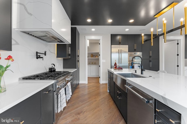 3113 Circle Hill Rd, Alexandria, VA 22305 - kitchen with custom exhaust hood, high quality appliances, dark cabinetry, light wood-type flooring, and tasteful backsplash