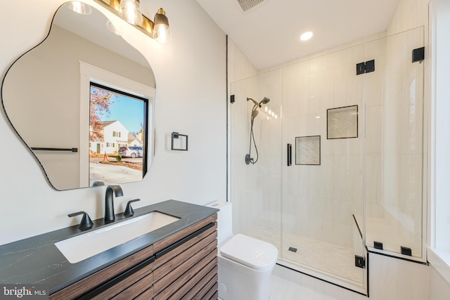 bathroom featuring a shower with door, vanity, and toilet