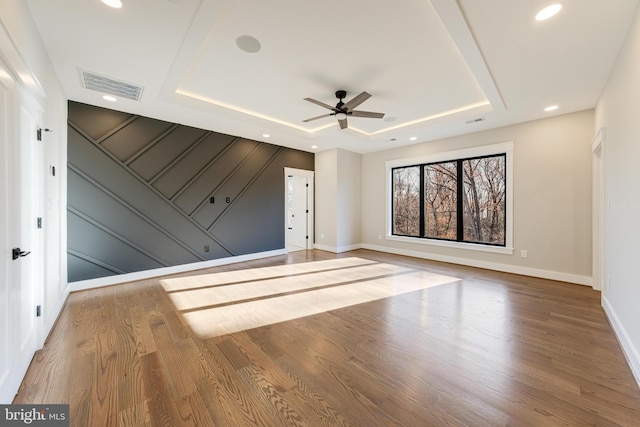 unfurnished room featuring wood-type flooring, a raised ceiling, and ceiling fan